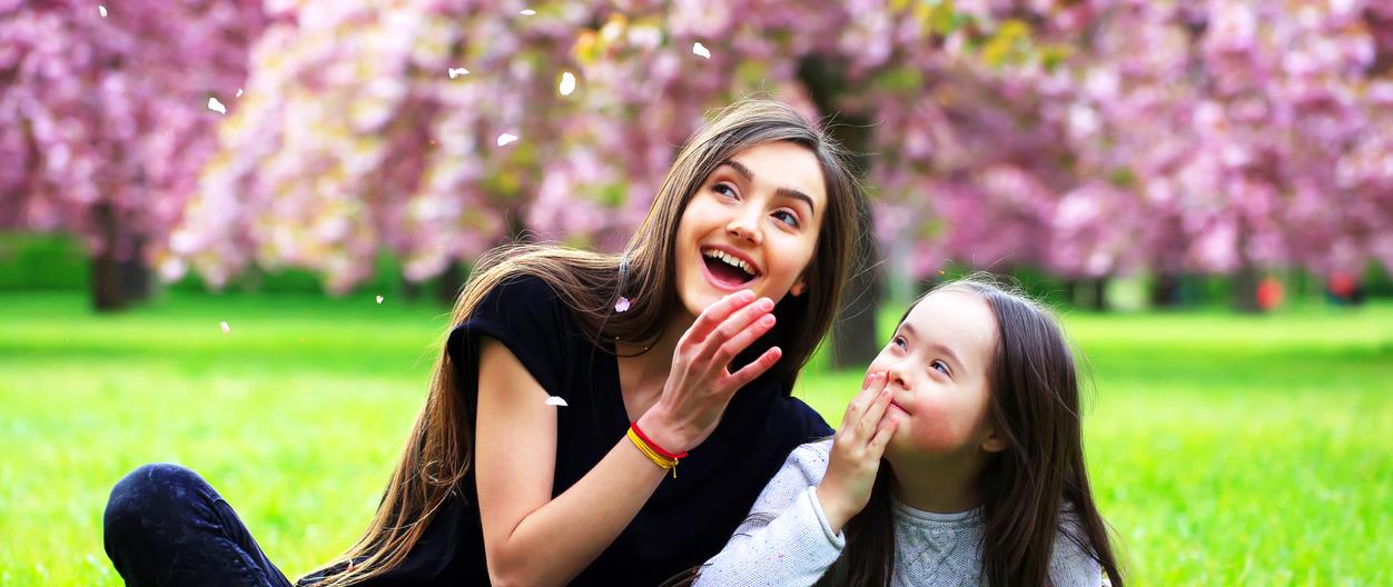 Woman and girl blowing flower petals